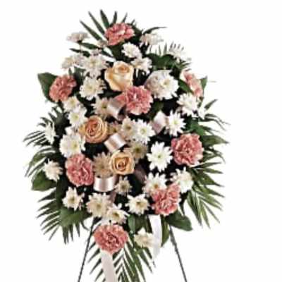 Standing spray of peach roses, pink carnations, and white daisies on a metal easel.