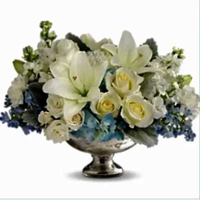 Low white lily and rose arrangement with blue accents in a silver pedestal bowl