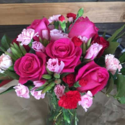 Arrangement of hot pink roses and pink and red carnations in a clear glass vase