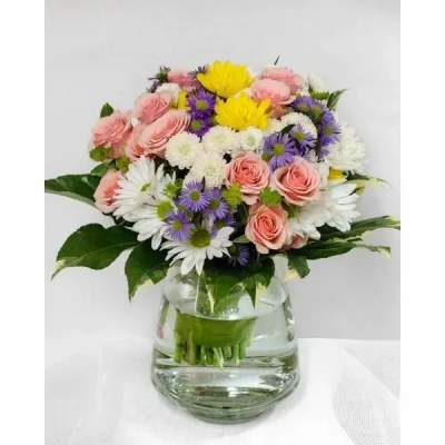Mixed bouquet of pink roses, white daisies, and purple asters in a clear glass vase