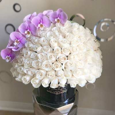 White rose bouquet with purple orchids in a metallic vase