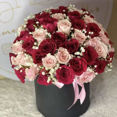 Round bouquet of red and blush roses in a black box with a pink ribbon