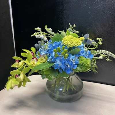 Blue hydrangeas and green orchids in a glass vase