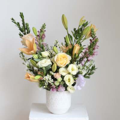 Mixed bouquet of lilies, roses, and lisianthus in a white vase