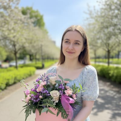 Woman holding a pink box of mixed pink and purple flowers