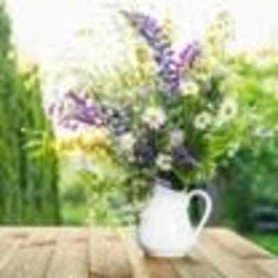 Purple and white flowers in a white pitcher on a wooden table