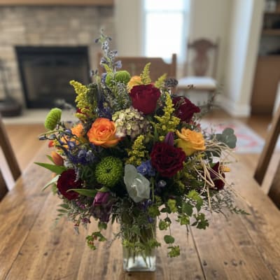 Mixed bouquet of roses and colorful flowers in a glass vase