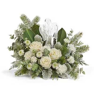 White roses and greenery arranged around a clear angel figurine