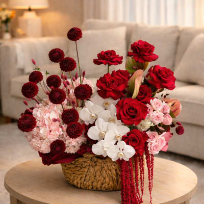 Red and pink floral arrangement in a woven basket on a round table