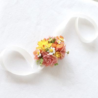 Small bouquet with pink and yellow flowers tied with white ribbon