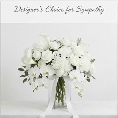 White floral arrangement in a clear glass vase with trailing ribbon