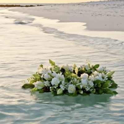 White floral arrangement floating on water at the beach