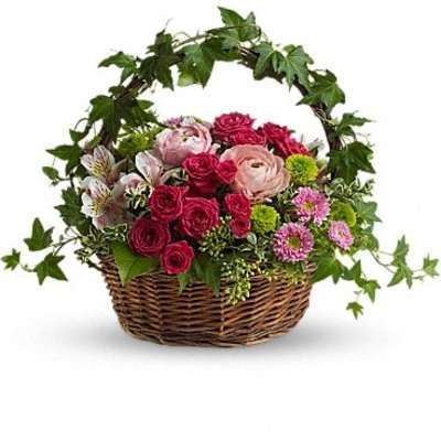 Basket of pink and red flowers with ivy arching over the top