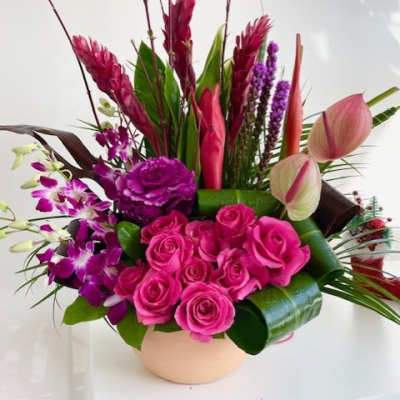 Pink roses and purple orchids arranged in a low vase