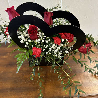 Red roses and carnations arranged in a black heart-shaped holder