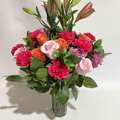 Bouquet of pink and orange roses with lilies in a clear glass vase