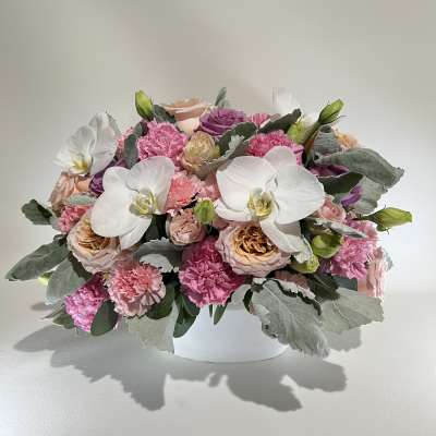 Pink and white floral arrangement in a white container