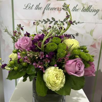 Mixed bouquet of pink and green flowers in a square glass vase