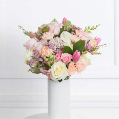 Pastel bouquet of roses, tulips, and carnations in a white vase