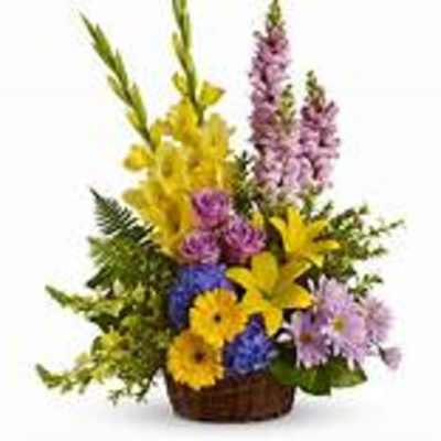 Basket arrangement with yellow lilies, purple flowers, and blue daisies