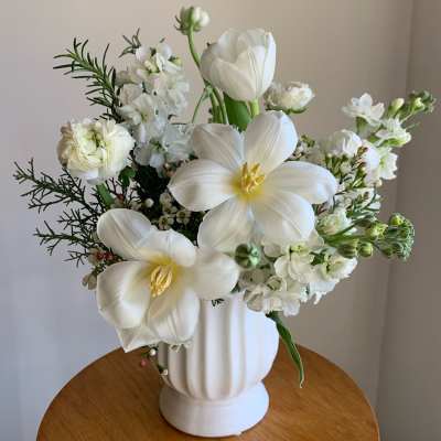 White floral arrangement in a white vase with large tulip-like blooms