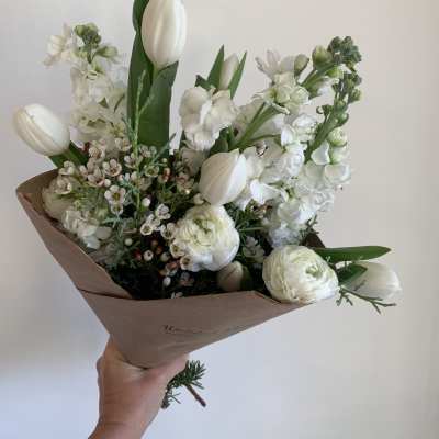 White tulips and ranunculus in brown paper wrapping