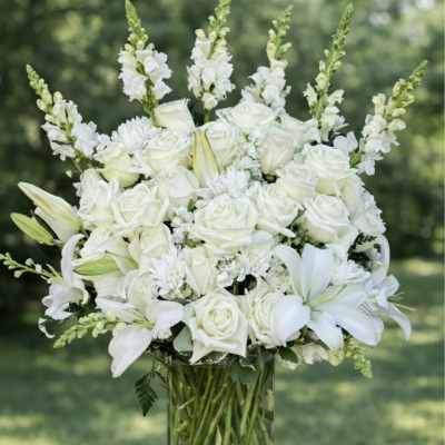 White roses and lilies arranged in a clear glass vase