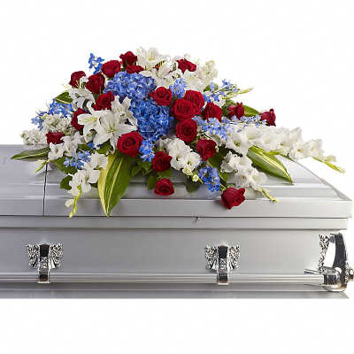 Red roses, white lilies, and blue flowers arranged on a silver casket