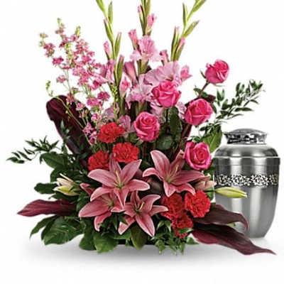 Pink and red floral arrangement beside a silver urn