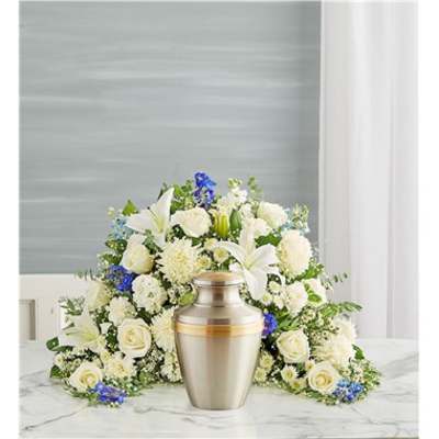 White floral funeral spray with a silver urn in front