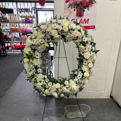Large white floral wreath on a black stand with clear water basins below.