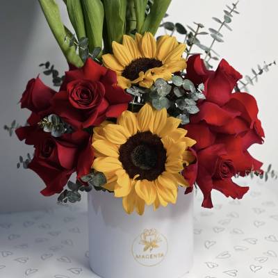 Red roses and sunflowers in a white hat box with white tulips