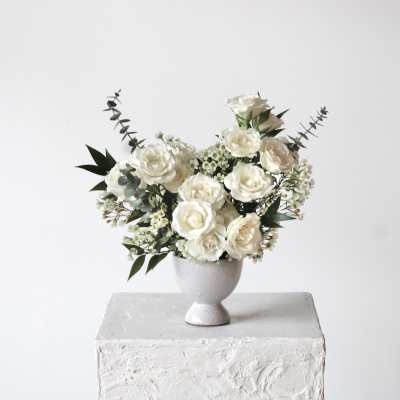 White rose arrangement in a small pedestal vase