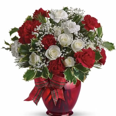 Red and white carnations and roses in a red glass vase with a plaid bow
