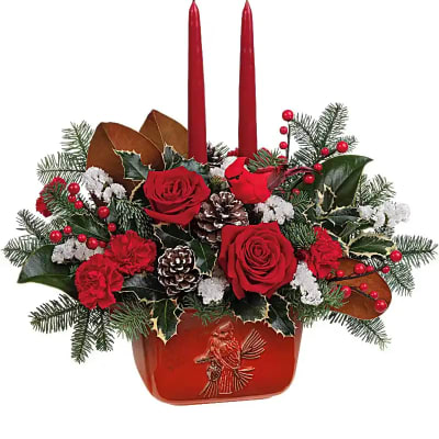Red rose arrangement with two red taper candles in a decorative container
