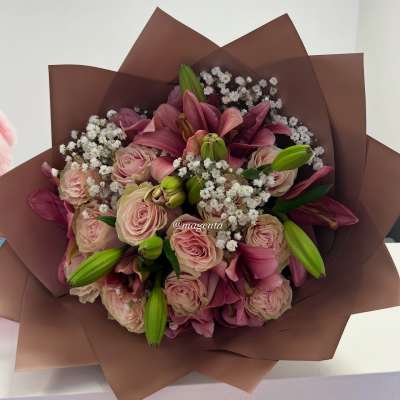 Bouquet of pink roses and lilies wrapped in brown paper