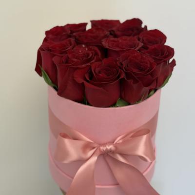 Bouquet of red roses in a pink hat box with a satin ribbon