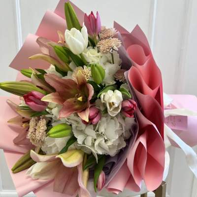 Pink and white bouquet with lilies and tulips wrapped in pink paper