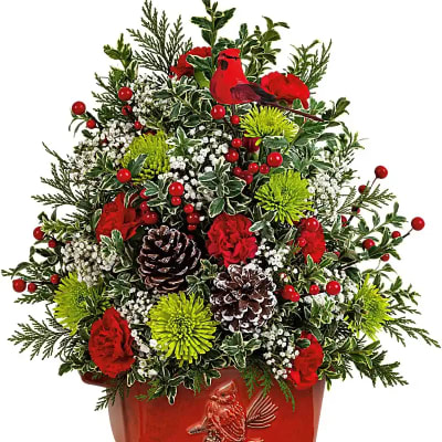 Christmas arrangement with red flowers, pinecones, and a red cardinal planter