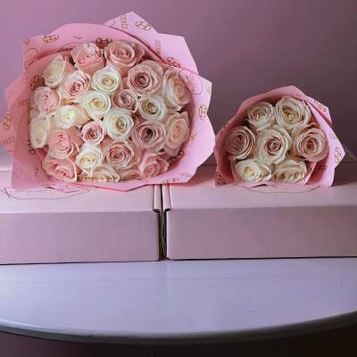 Two bouquets of pale pink and cream roses wrapped in pink paper