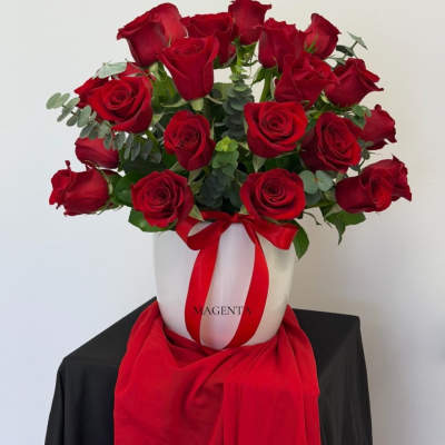 Red roses arranged in a white hatbox with a red ribbon