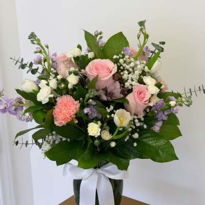 Pink and white mixed bouquet in a glass vase with a white ribbon