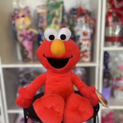 Red Elmo plush toy sitting on a stool