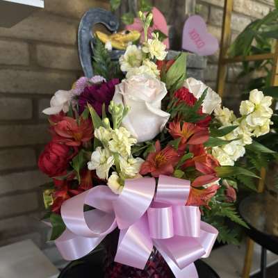 Mixed bouquet of roses and alstroemeria in a pink vase with a large ribbon