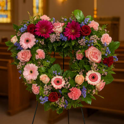 Heart-shaped floral wreath on an easel with pink and red flowers