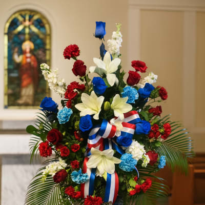 Standing floral spray with red, white, and blue flowers on an easel
