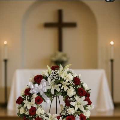 Red and white floral funeral wreath on a stand in a church