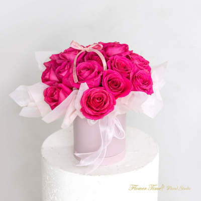 Hot pink roses arranged in a pale pink box with a ribbon bow