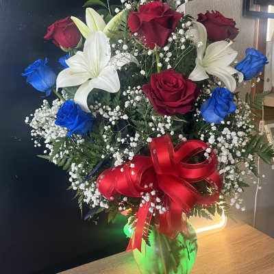 Bouquet of red and blue roses with white lilies in a glass vase
