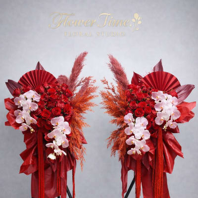 Two red floral standing arrangements with pink orchids on black stands